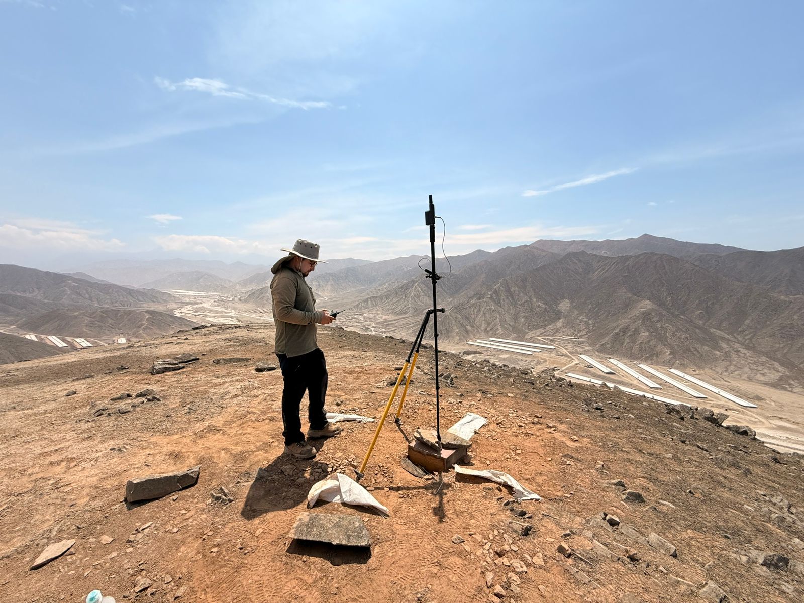 Operator working beside a GNSS base station in mountainous terrain